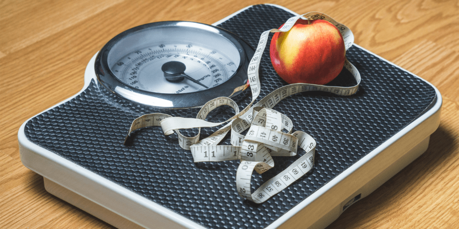 Immagine rappresentativa di una bilancia con sopra una mela ed un metro, utilizzata come simbolo del calcolo delle calorie